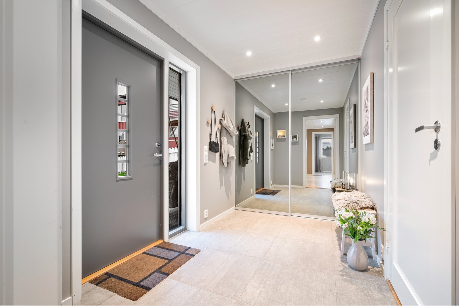 Entréen er lys og trivelig, med pent og flislagt gulv og skyvedørsgarderobe for yttertøy Galleribilde