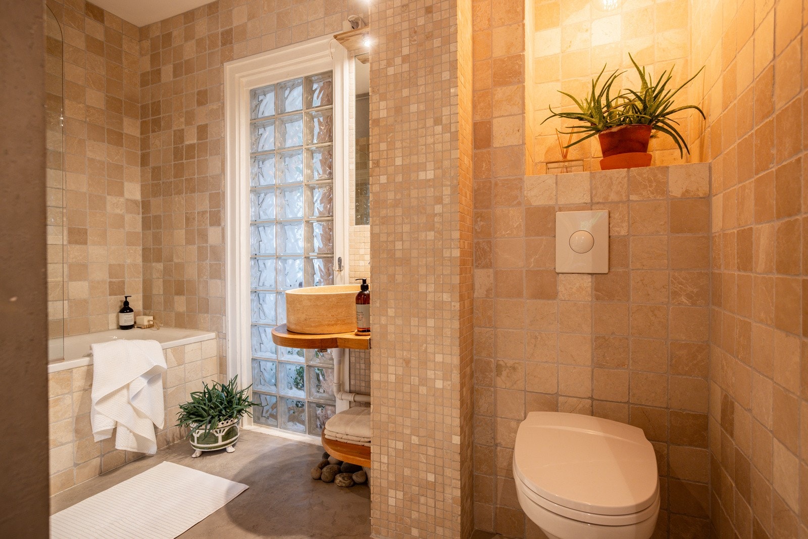 Badet har badekar og varmekabler på gulvet. Det er opplegg for vaskemaskin ved glassmestersteinene. Galleribilde