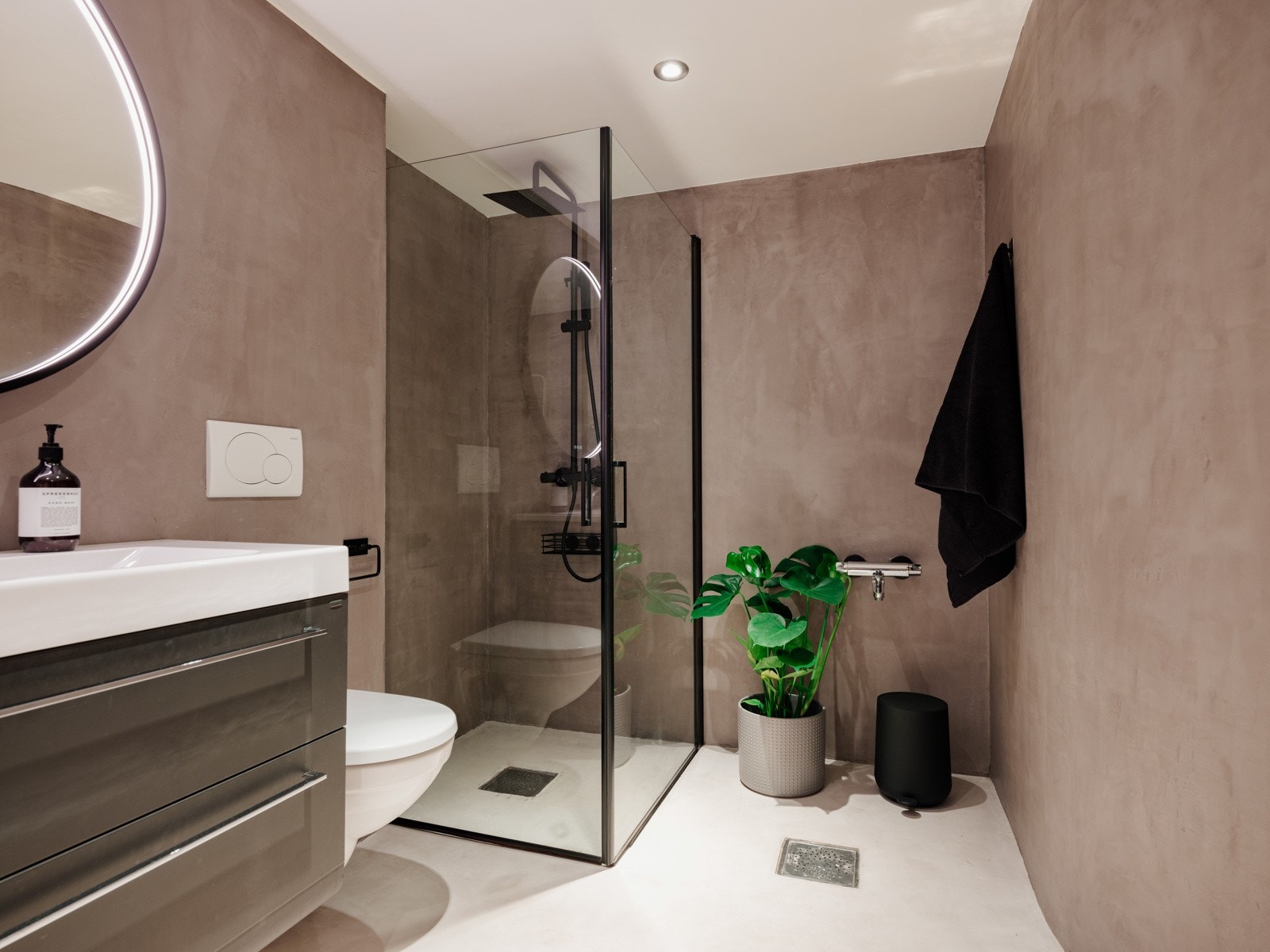 Baderommet inneholder servant med underskap, speil med belysning, vegghengt toalett og dusjhjørne med innfellbare dører og regnfallsdusj. Galleribilde