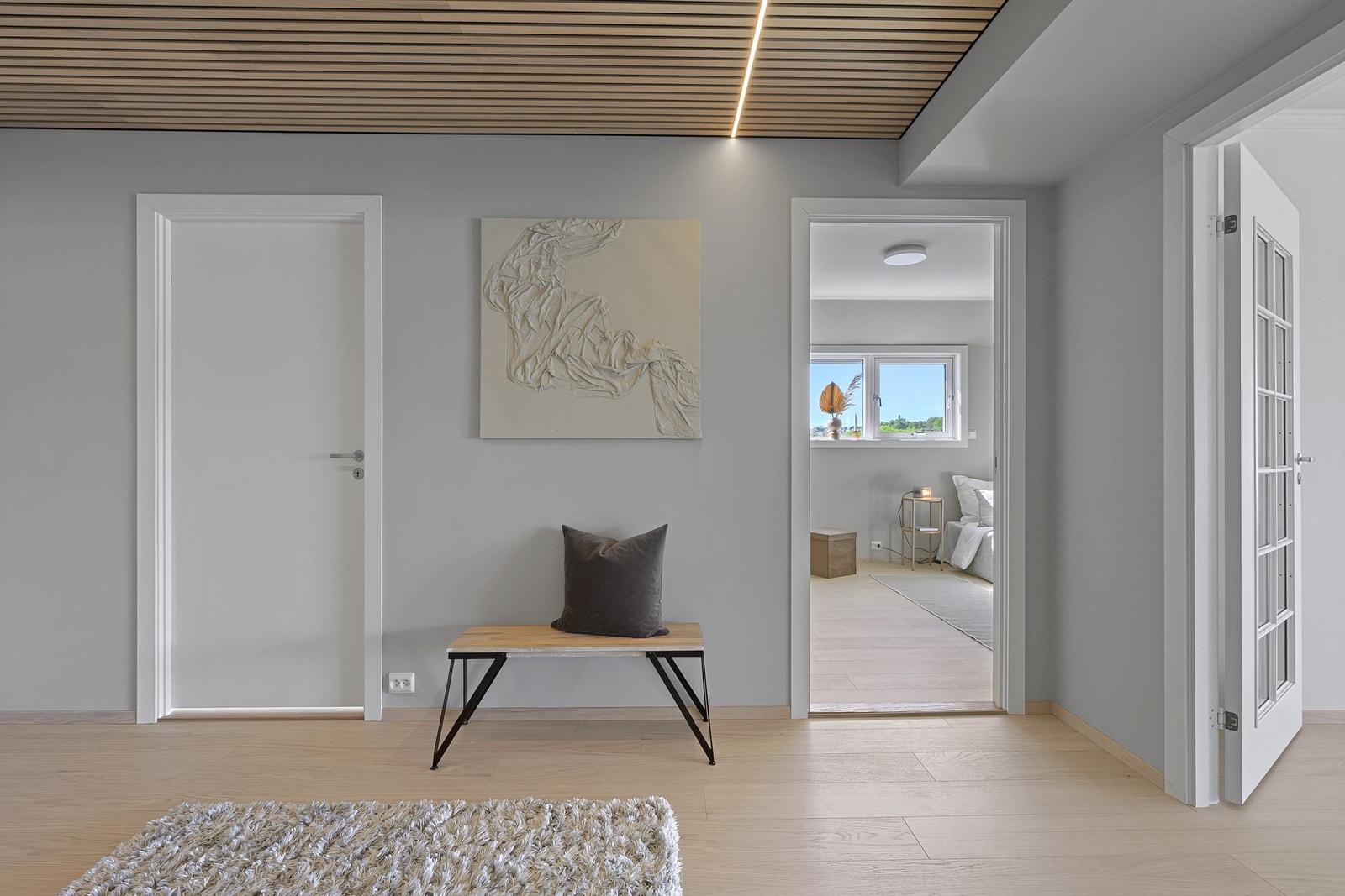 Entrè / gang med dører inn til 2 av soverommene. Doble glassdører på høyre side vender inn mot stue/kjøkken. Galleribilde