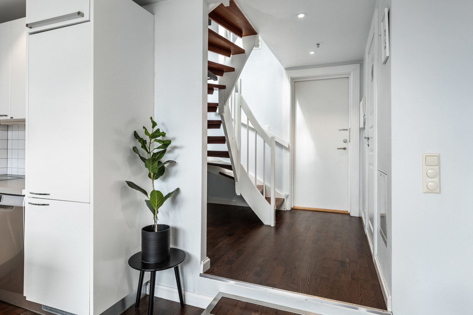 Entreen har moderne overflater med mørkt laminatgulv og slette, gråmalte vegger. Galleribilde