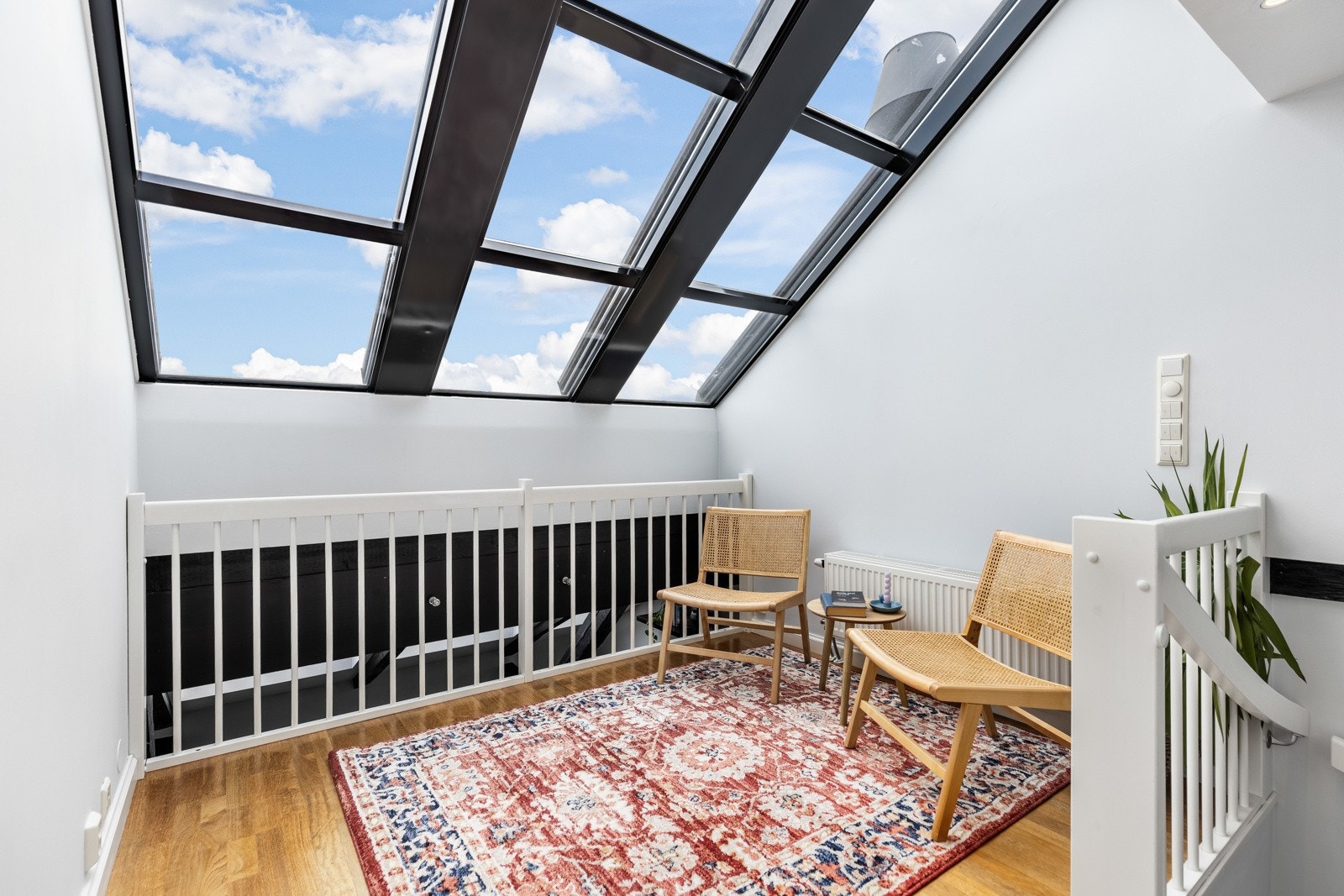 Mesaninen har parkettgulv, hvitt rekkverk og vinduer som dekker hele skråtaket. Galleribilde