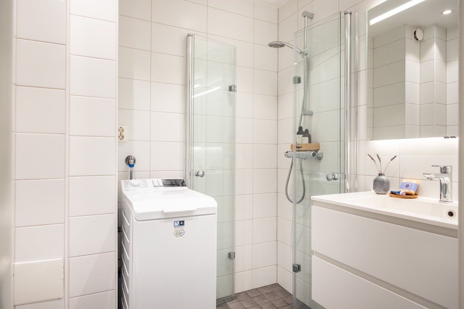 Badet består av toalett, hjørnedusj, servant med underskap og opplegg til vaskemaskin. Galleribilde