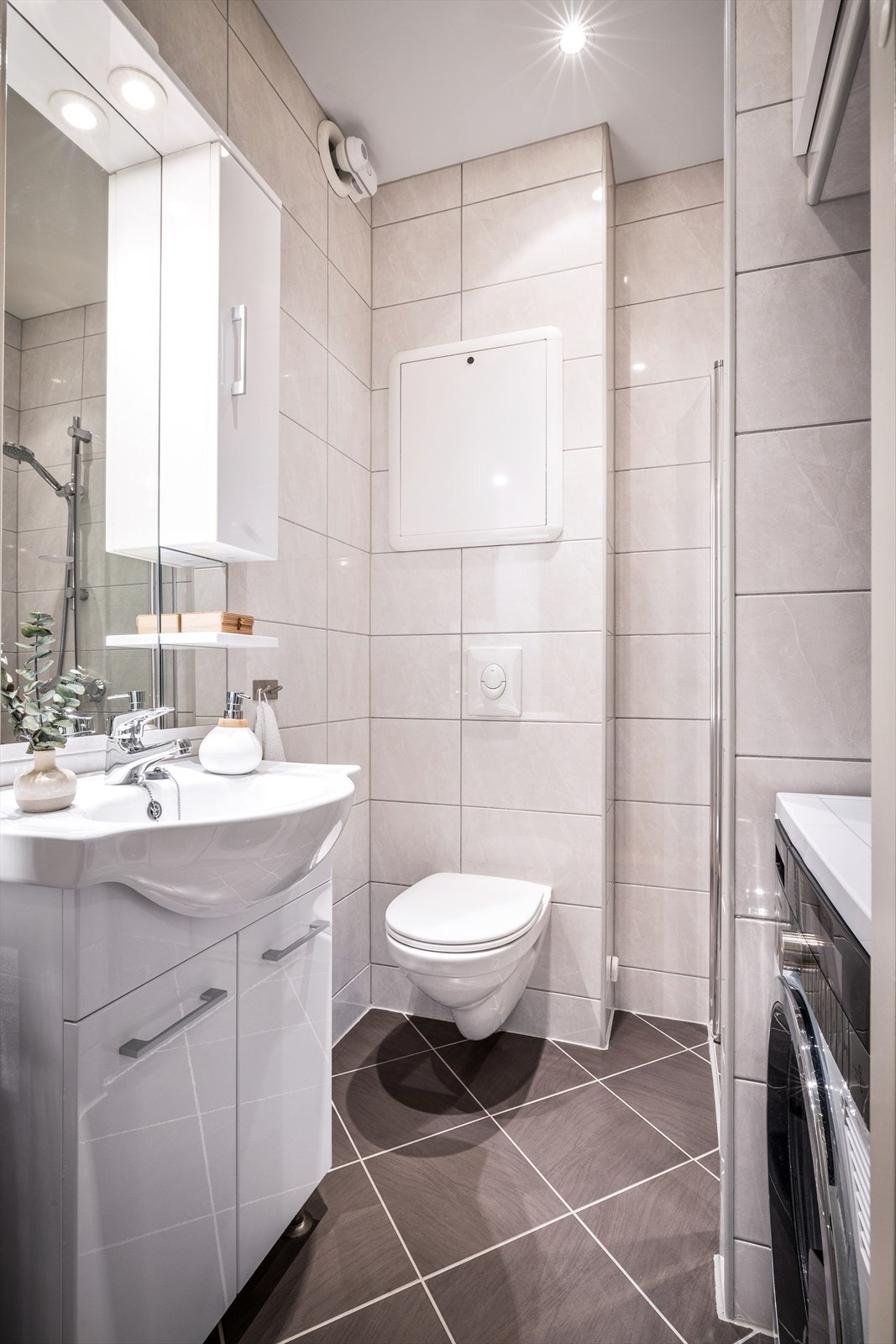 Badet er pent og helfliset, med mørkegrå fliser på gulv og lysbeige fliser på vegg. Galleribilde