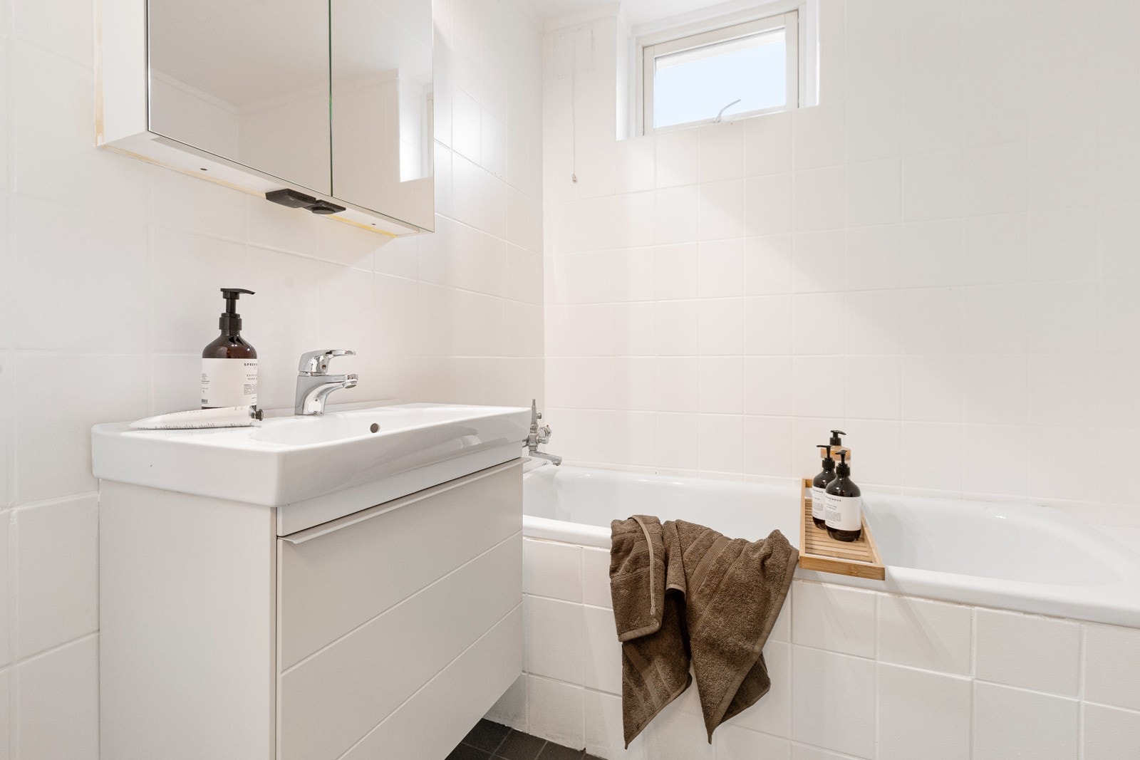 Praktikantdel: Badet er flislagt med gulvvarme og har innebygd badekar, servant med benkeskap og overskap med speilfronter. Galleribilde