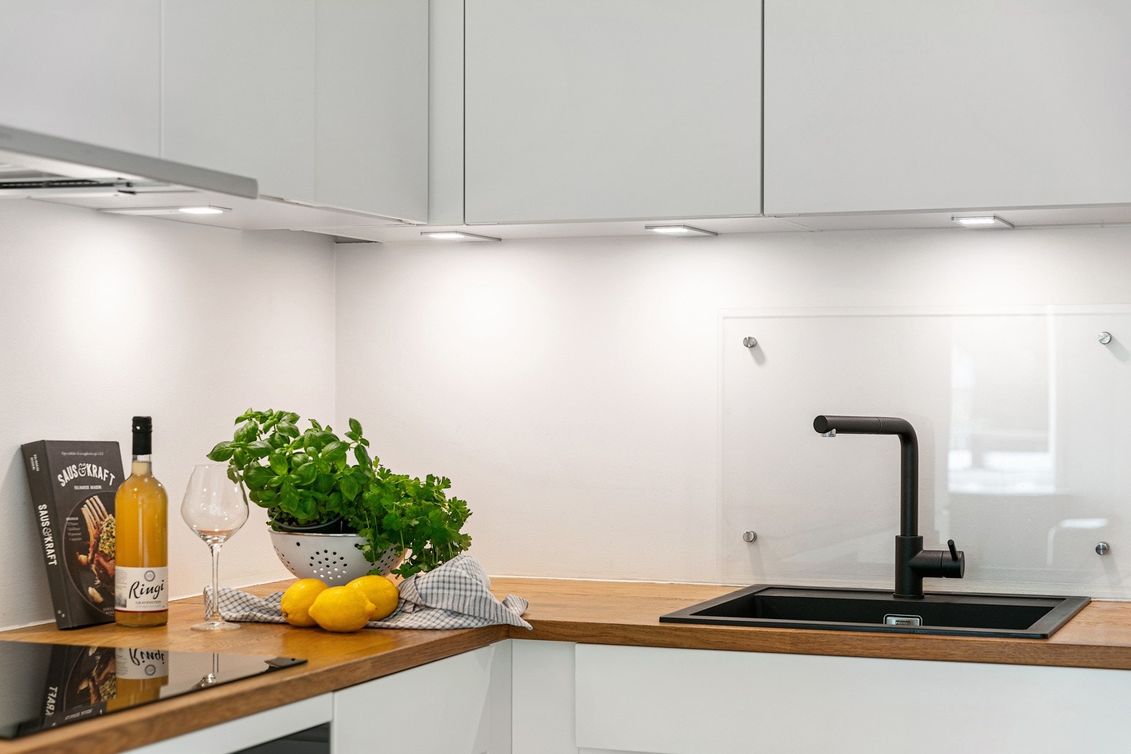 Benkeplater i tre, med nedfelt kum av kompositt med ettgreps blandebatteri. Glassplate over benkeplate ved vask Galleribilde