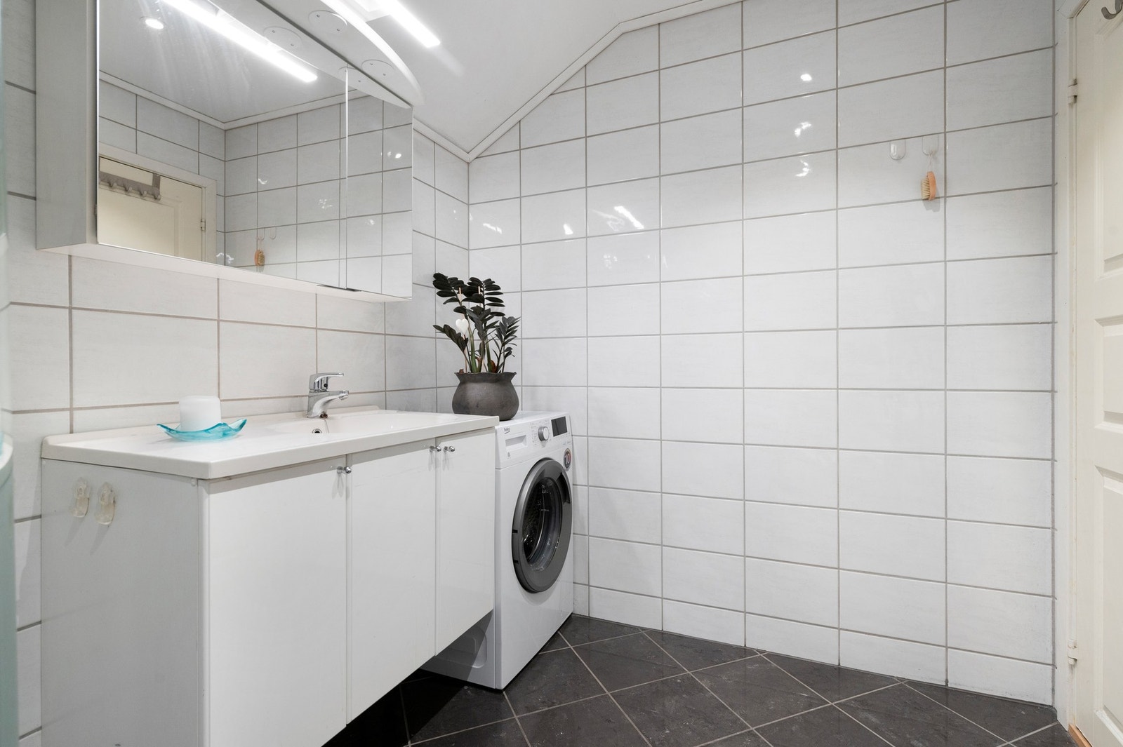 Badet er utstyr med dusjkabinett, servant med skap, toalett og opplegg for vaskemaskin. Galleribilde