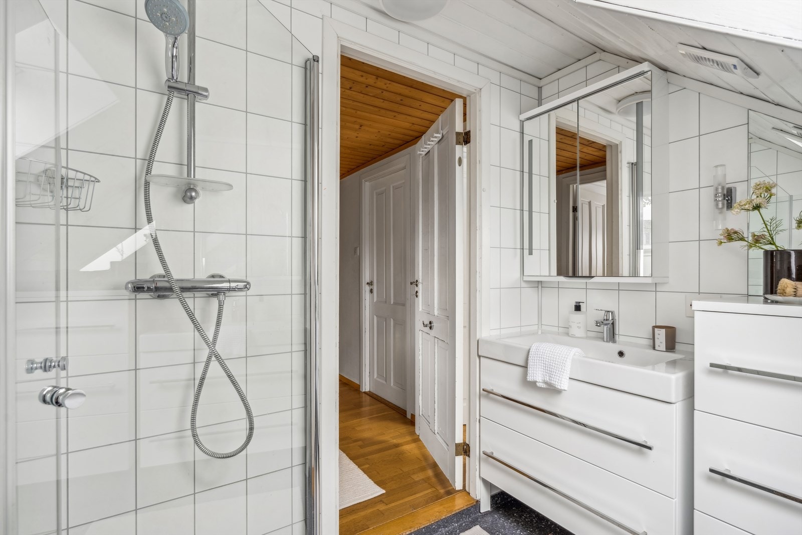 Badet har innredning med nedfelt servant, dusjhjørne med glassvegger og toalett, elektrisk vifte i veggen. Galleribilde