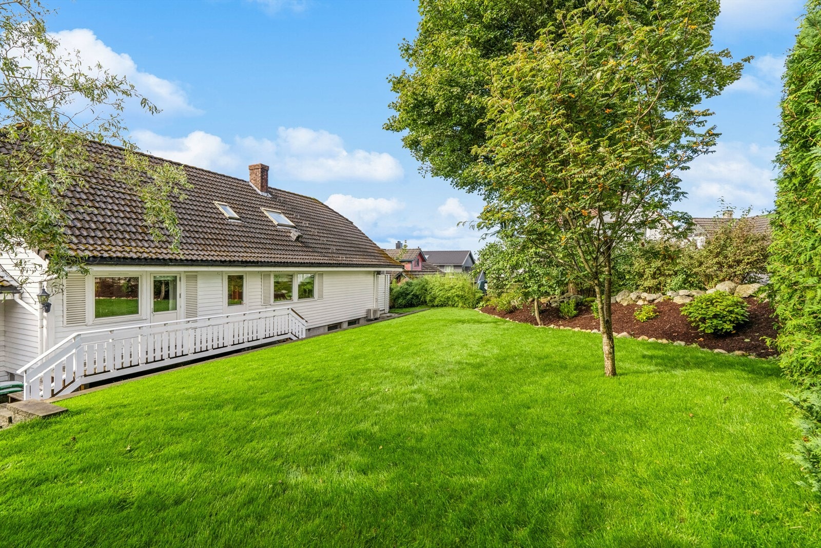Pen opparbeidet hage med gressplen og diverse beplantning. Galleribilde