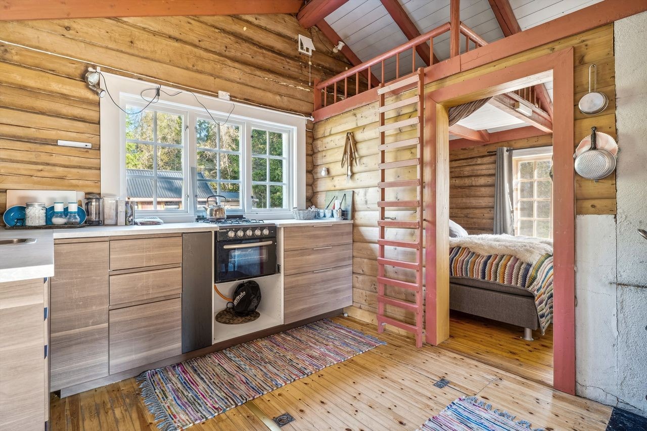 Kjøkkenet har tømmer på veggene og tregulv. Kjøkkeninnredning med laminerte, glatte fronter og laminerte benkeplater i hjørneløsning. Innredningen består av underskap og skuffer. Det er en eldre skapseksjon montert som overskap i hjørnet. Galleribilde