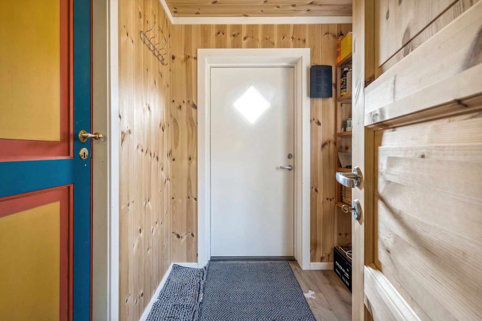 Vindfang med panel på veggene og laminat på gulvet. Her er det plass til å henge fra seg yttertøyet før du går videre inn i hytta. Vindu på endeveggen slipper høstsolen inn i rommet. Galleribilde