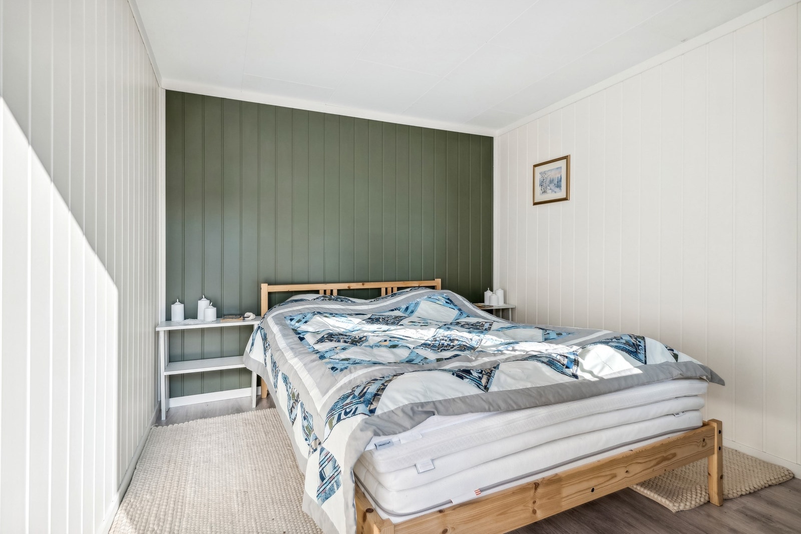 Rom i anneks innredet som soverom har hvitmalt panel på veggene, en grønnmalt kontrastvegg og laminat på gulvet. Galleribilde