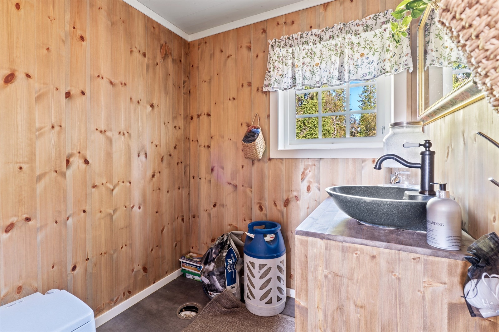 Stellerommet/vask har panel på veggene og grått belegg på gulvet. Rommet er innredet med servant montert på plassbygget benkeplate. Det er sluk i gulvet. Galleribilde