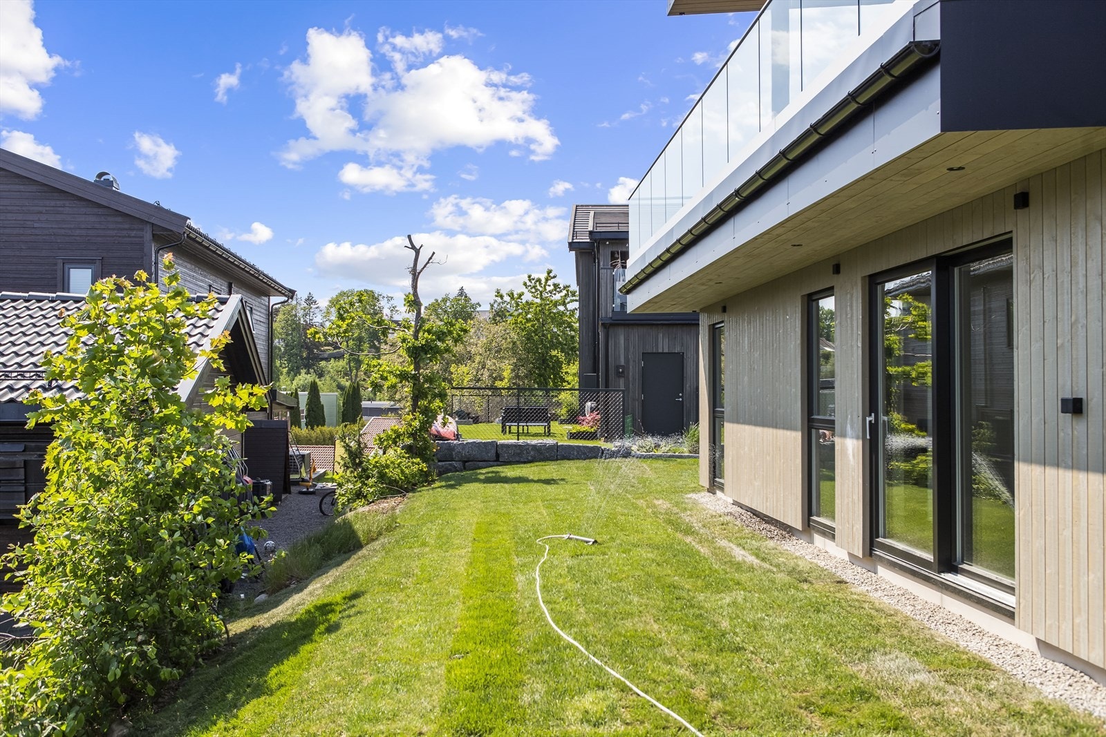 Tomten er pent opparbeidet med asfaltert gårdsrom i front og et lettstelt plenareal rundt deler av boligen. Galleribilde