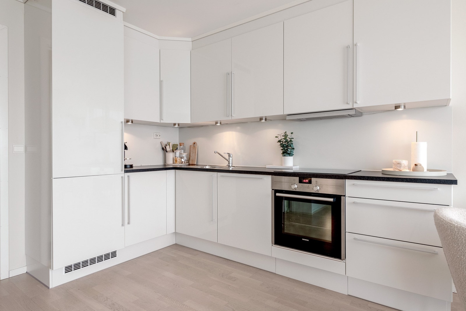 HTH kjøkkeninnredning med glatte fronter og benkeplate av laminat. Integrert stekeovn, platetopp, oppvaskmaskin og kjøleskap med fryser. Ventilator i overskap. Galleribilde