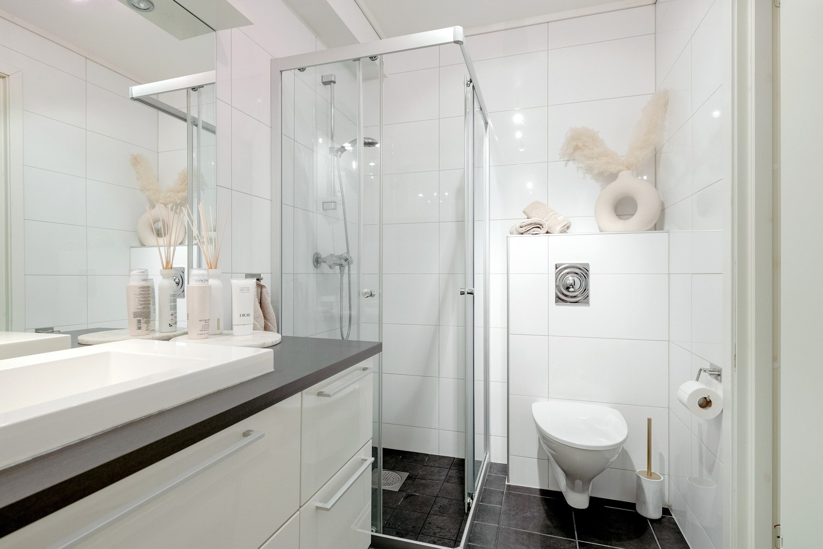 Badet har dusjhjørne med glassvegger og vegghengt toalett Galleribilde