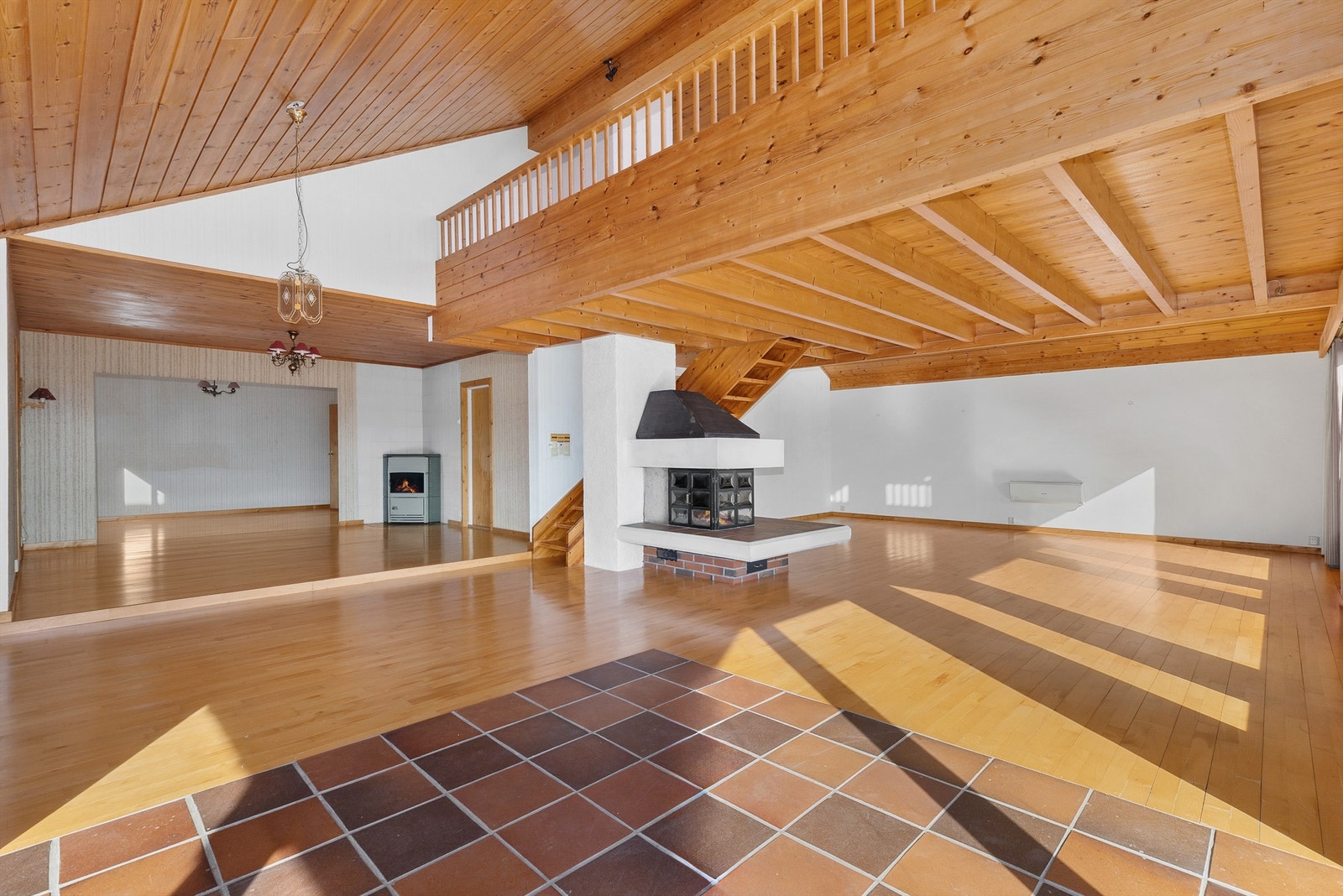 Midt i rommet er det peis og langs veggen er det montert varmepumpe. Galleribilde