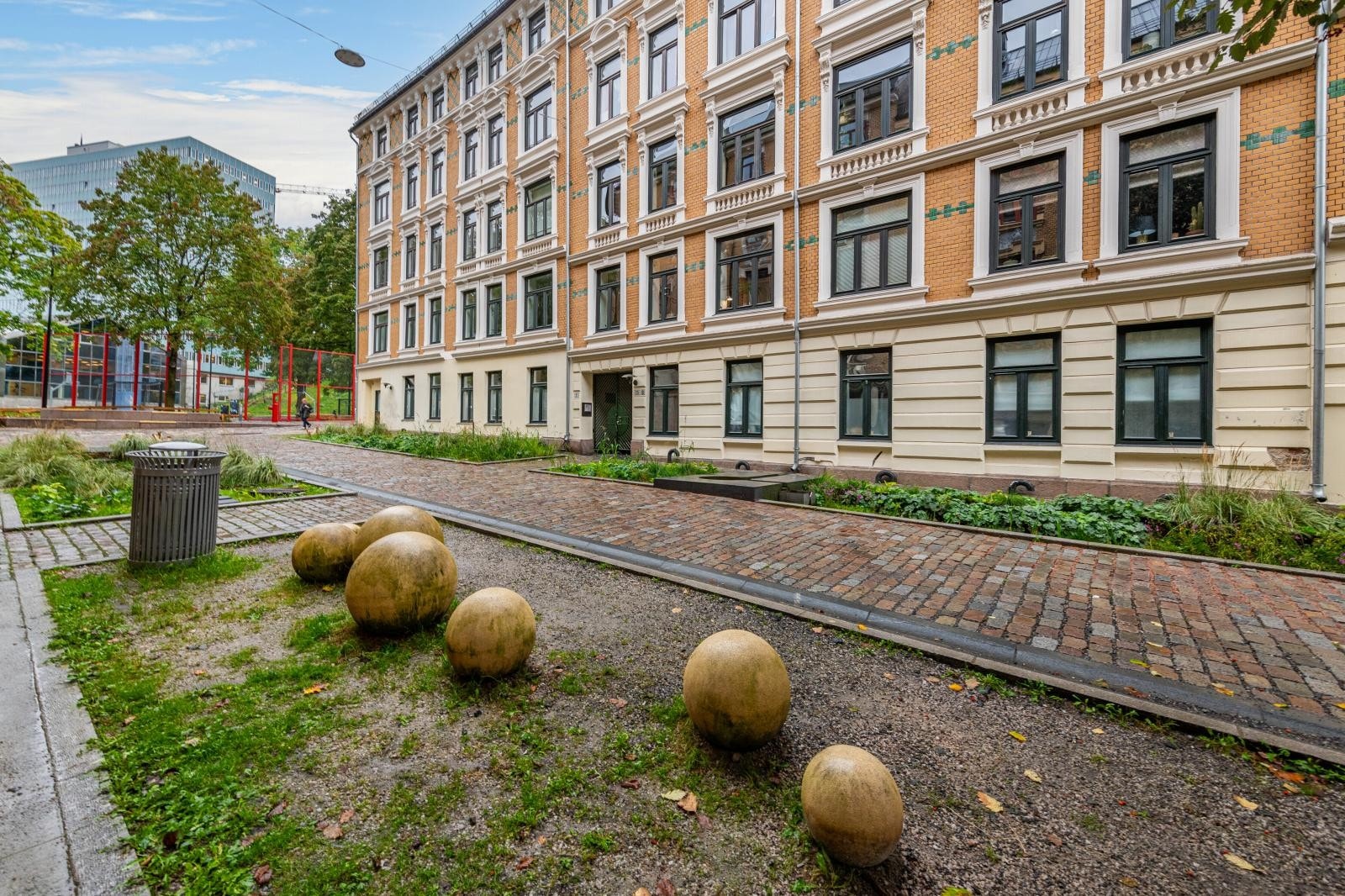 Blindvei som grenser til park med sittebenker og liten idrettsplass Galleribilde