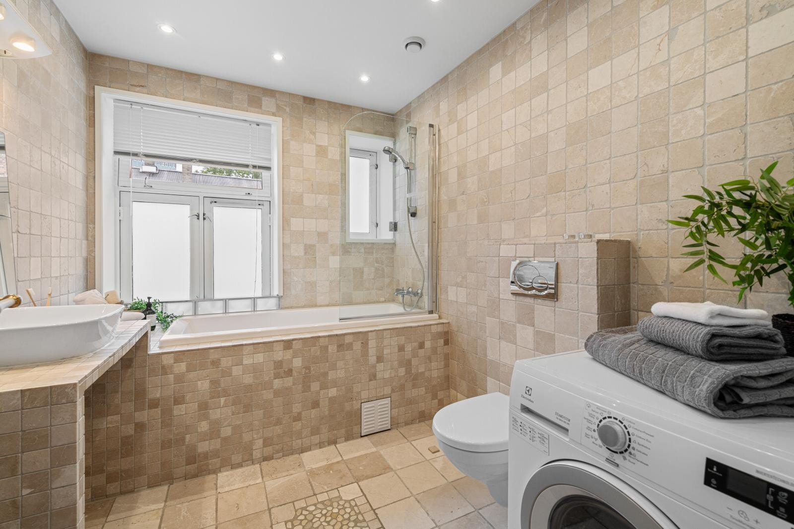 Badet er flislagt, har varmekabler og downlights, samt opplegg for vaskemaskin Galleribilde