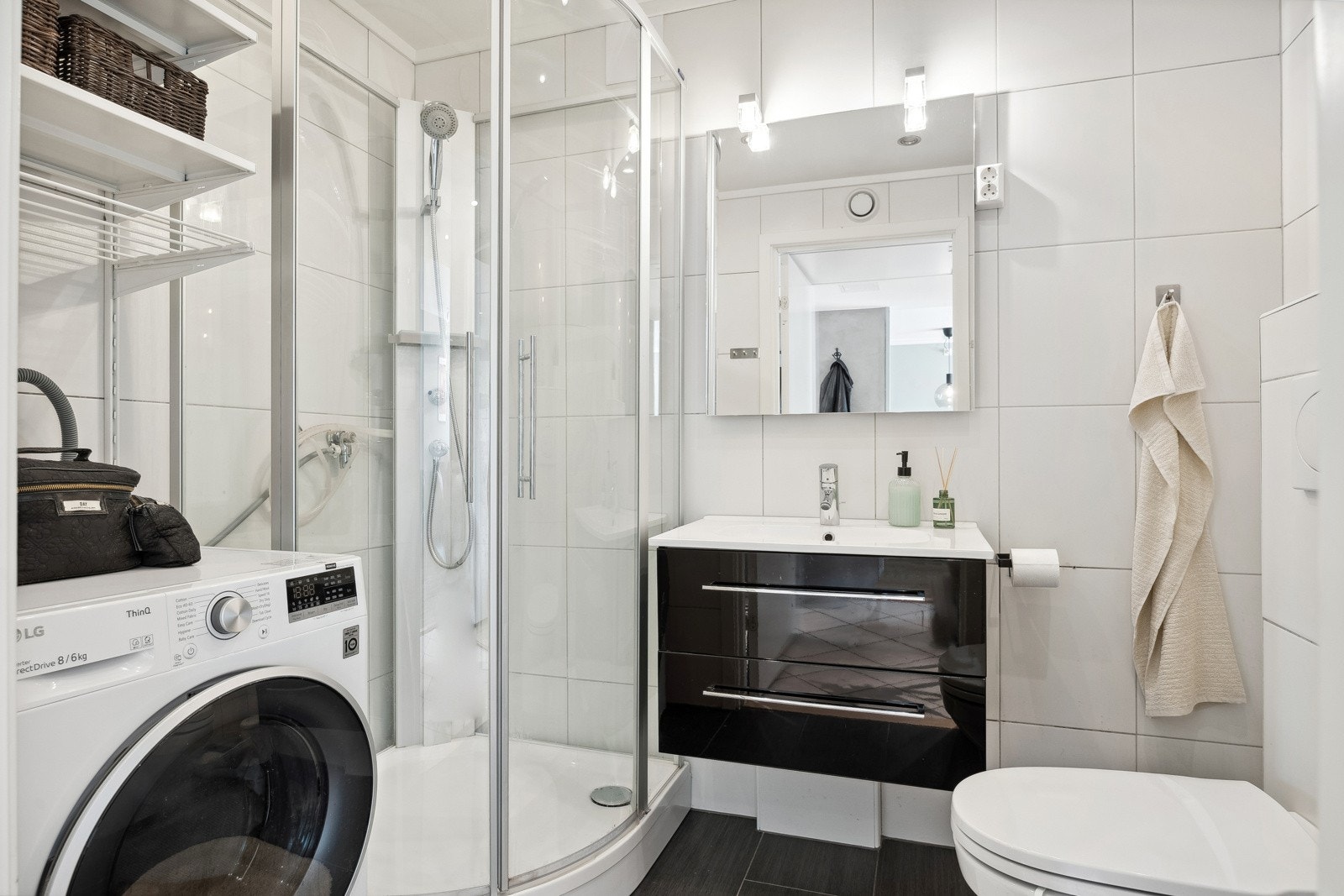 Badet er videre utstyrt med veggmontert toalett, servantskap med servant, opplegg for vaskemaskin, dusjkabinett og mekanisk avtrekk. Galleribilde