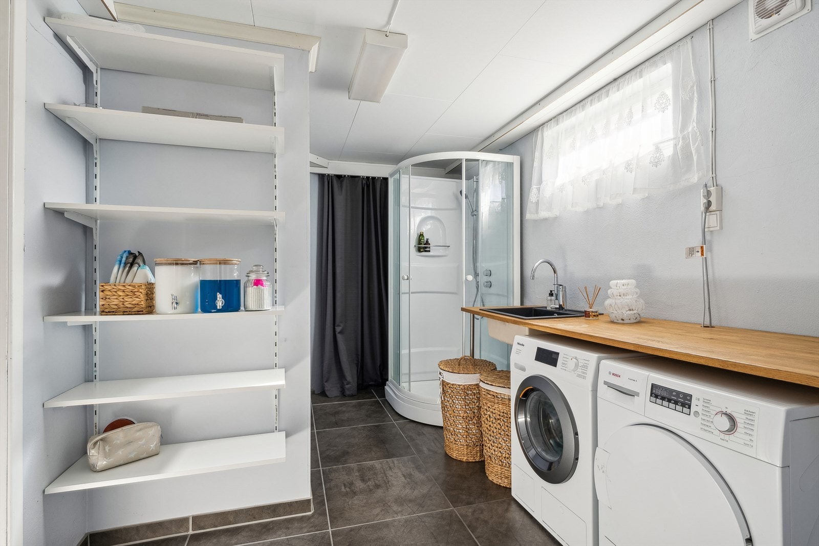 Kombinert vaskerom/dusjbad beliggende i boligens underetasje. Rommet er i opprinnelig stand fra byggeår, dog er det foretatt enkelte oppgraderinger med maling og gulvfliser over opprinnelig membran/dekke i 2016. Galleribilde