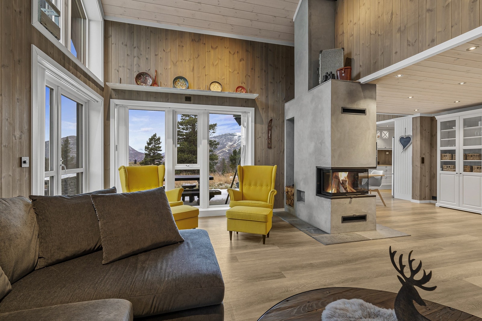 Romslig stue med flott peisovn som skiller mellom stue og spisestue / kjøkken Galleribilde