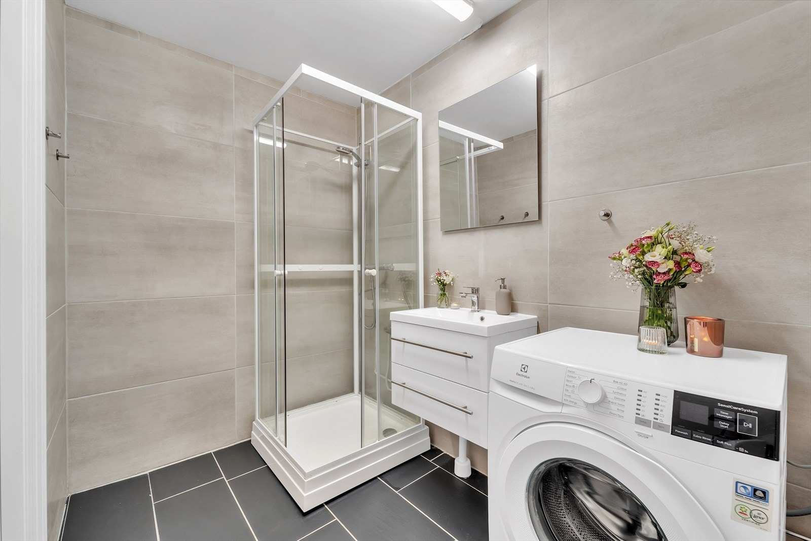 Badet inneholder dusjkabinett, servant med underskap, speil, toalett og opplegg for vaskemaskin. Galleribilde