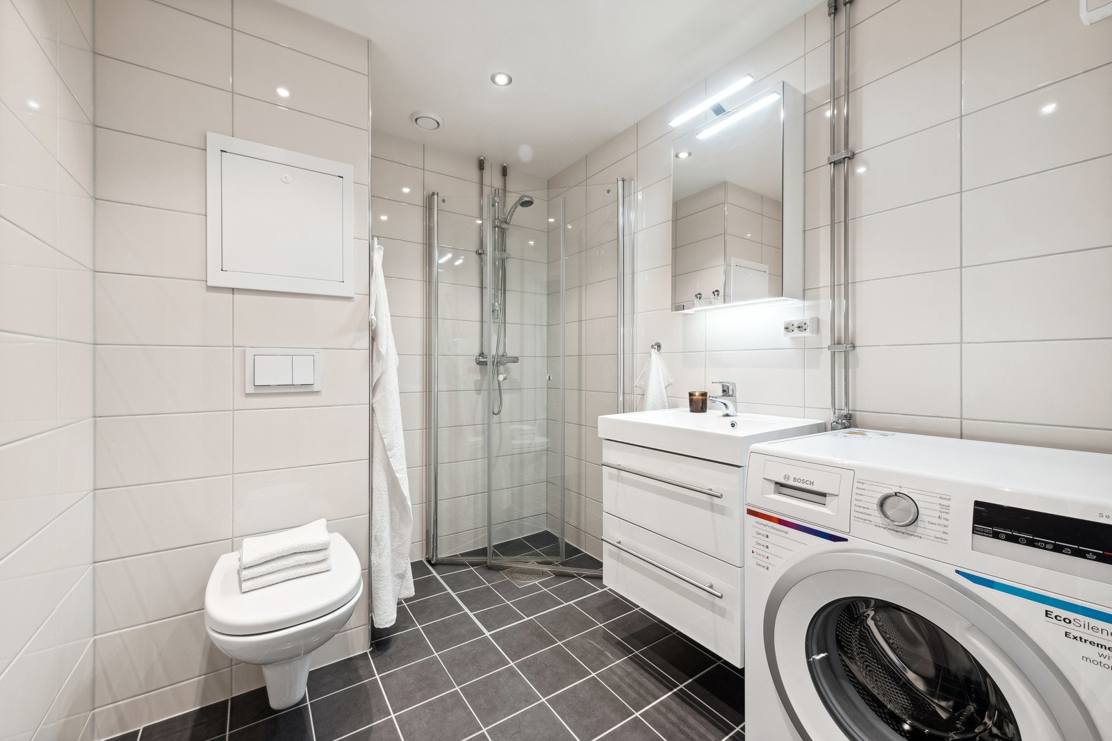Badet har flislagt gulv med varme, flislagte vegge og nedsenket himling med downlights. Galleribilde