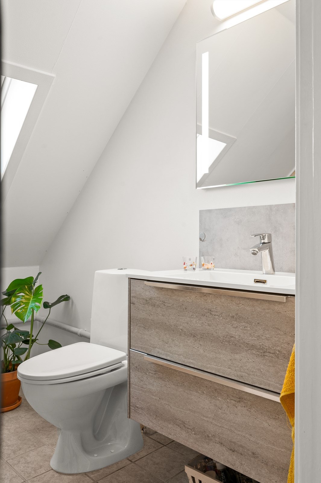 Vegghengt servantskap med ovenpåliggende servant, samt speil med lys over. Galleribilde