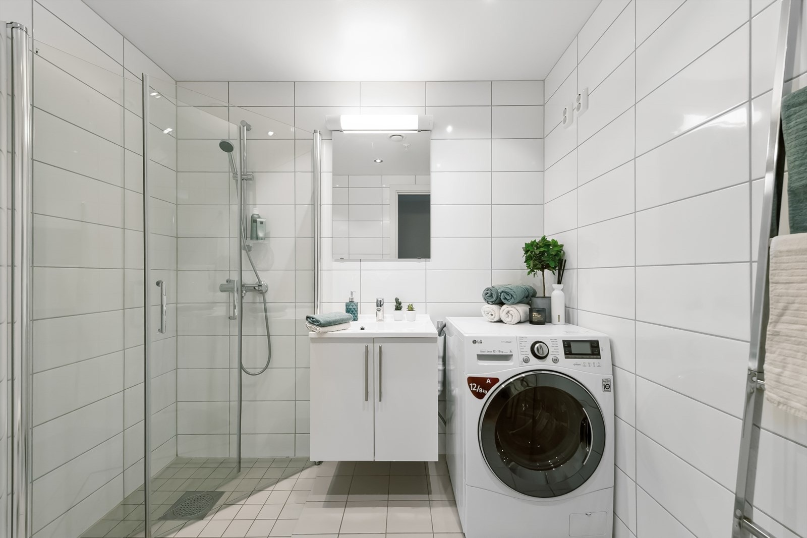 På badet er det montert servantinnredning, praktisk speil med belysning, vegghengt toalett, dusjhjørne og opplegg til vaskemaskin. Galleribilde