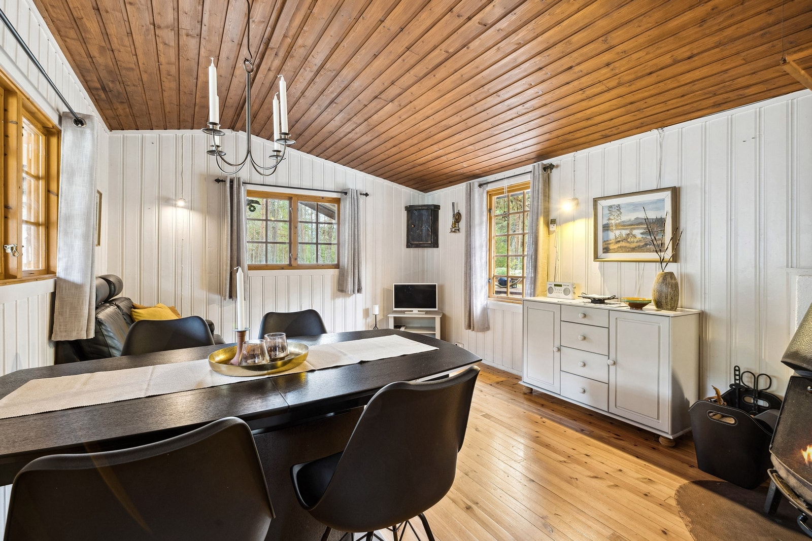 Det er åpen løsning mellom kjøkkenet og stuen. Rommet har hvitmalt panel på veggene og tregulv. Galleribilde