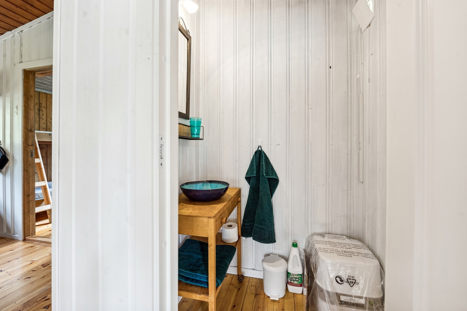 Hygienerommet har hvitmalt panel på veggene og tregulv. Rommet er innredet med enkel innredning med vaskeservant og portabel toalett. Det er ikke innlagt vann og avløp i rommet. Ventil på vegg. Galleribilde