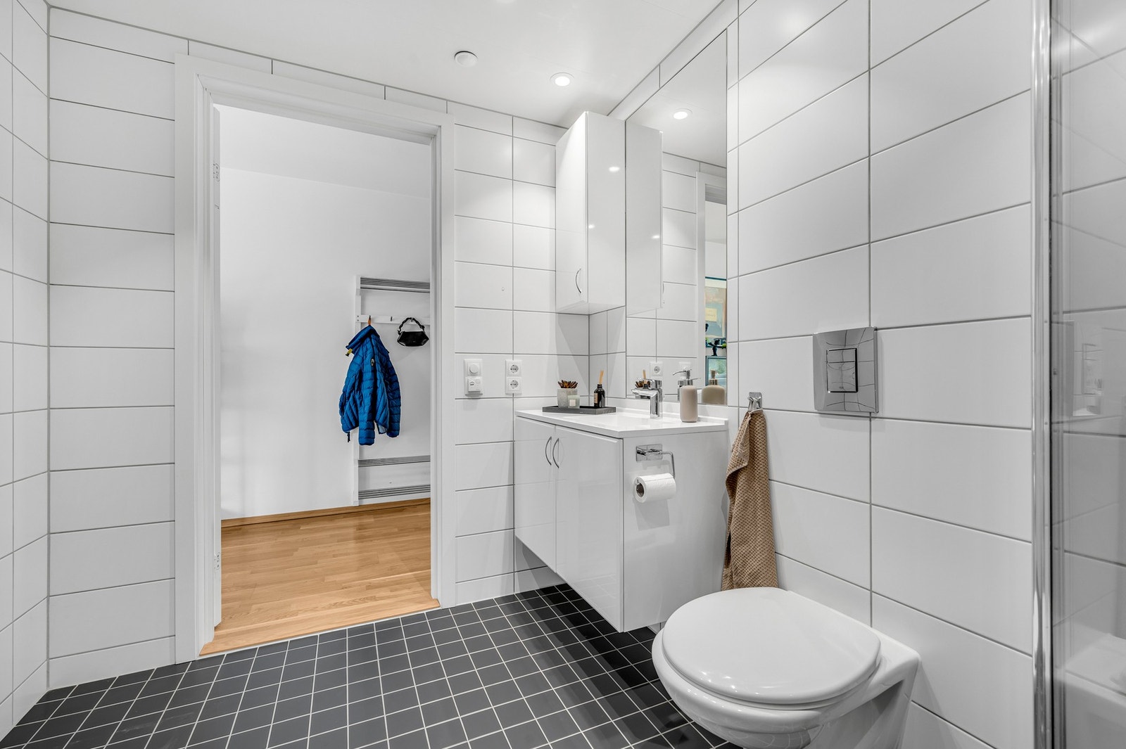 Badet inneholder bl.a dusjhjørne, vegghengt WC, servant, baderomsinnredning og opplegg for vaskemaskin Galleribilde