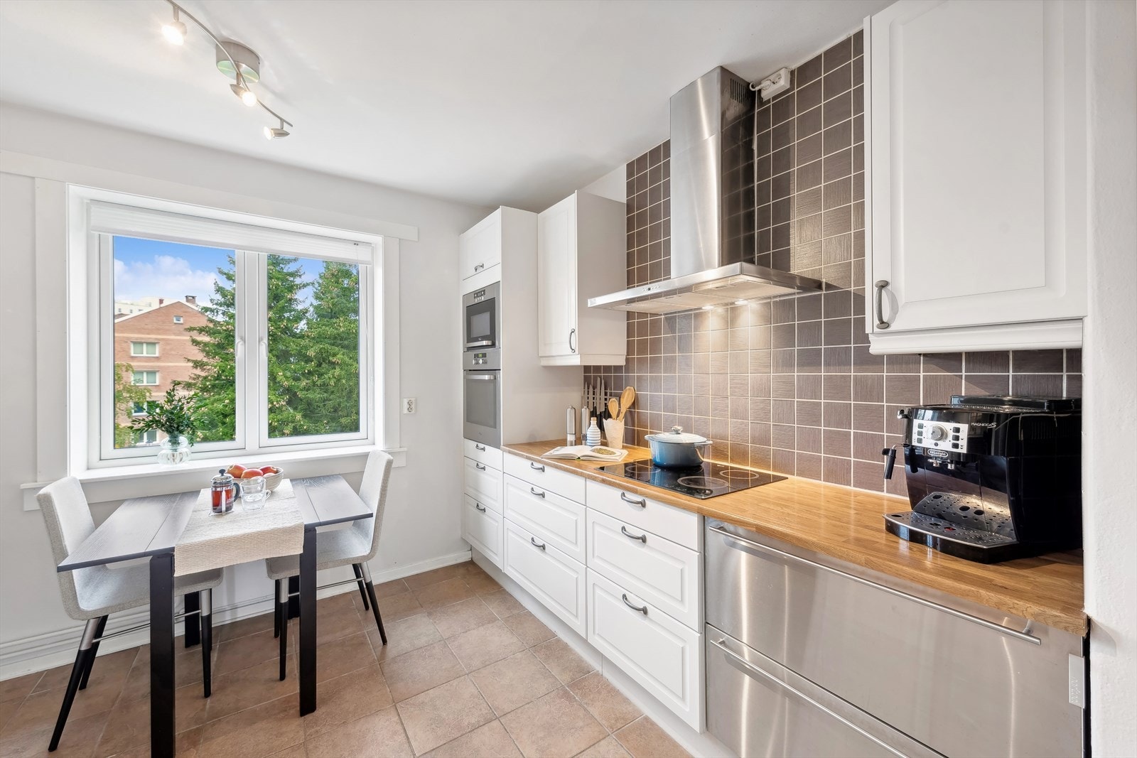 Kjøkkeninnredningen har profilerte fronter, glassfronter og belysning i overskapene. Fliser over benkeskap og laminat benkeplate med nedfelt kum i rustfritt stål. Galleribilde