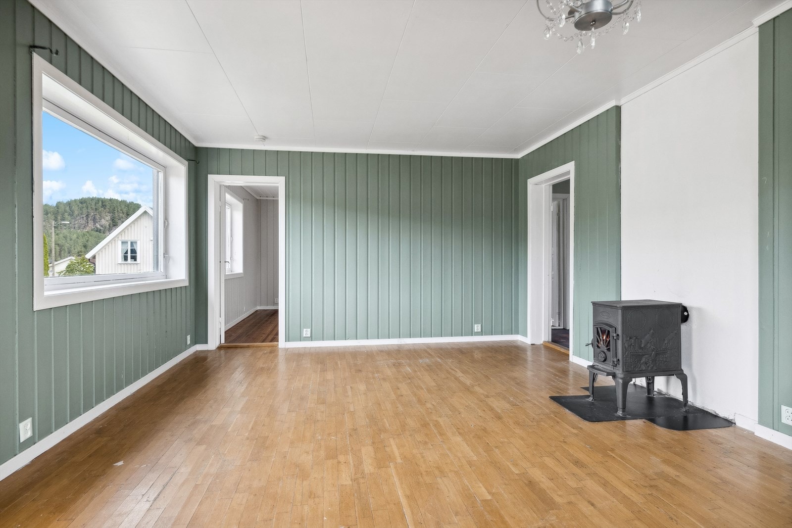 Stua har en moderne grønnfarge med en vedovn som varmer på kalde vinterdager. Galleribilde