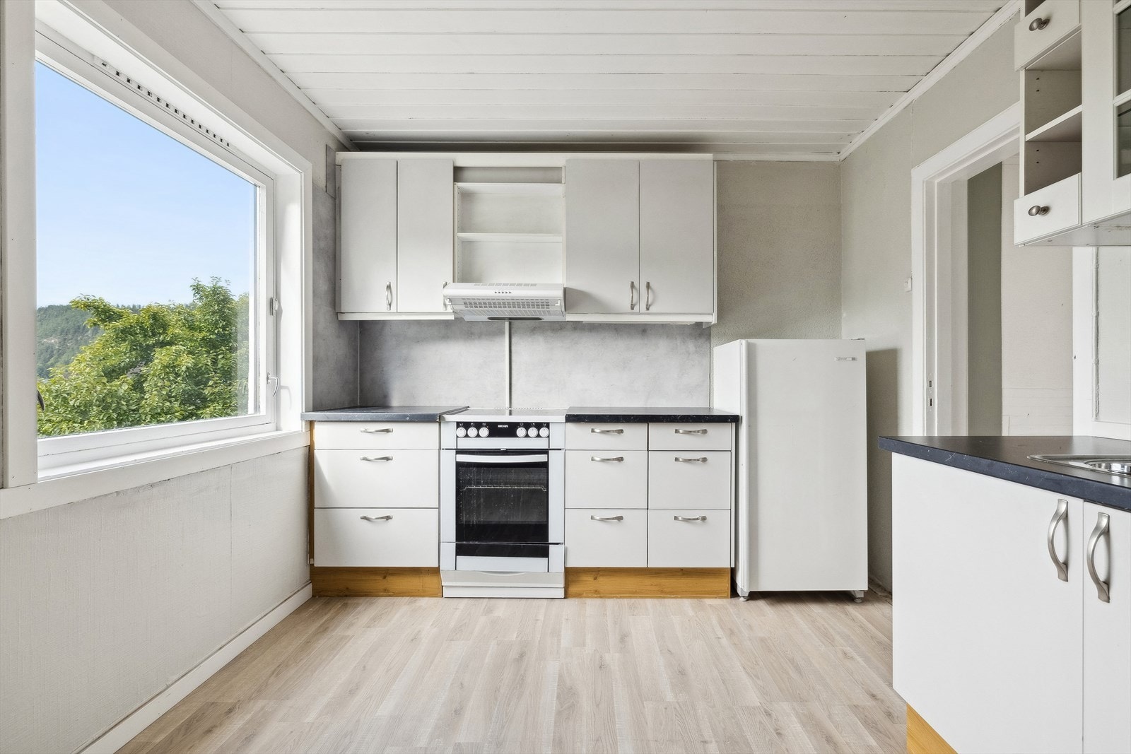 Kjøkkenet i andreetasje er praktisk med gode løsninger. Kjøkkenet har innredning med flatte fronter, benkeplate av laminat og opplegg for vaskemaskin. Det er også godt med lagringsplass i skap og hyller. Rommet fremstår lyst med lyse vegger. Galleribilde