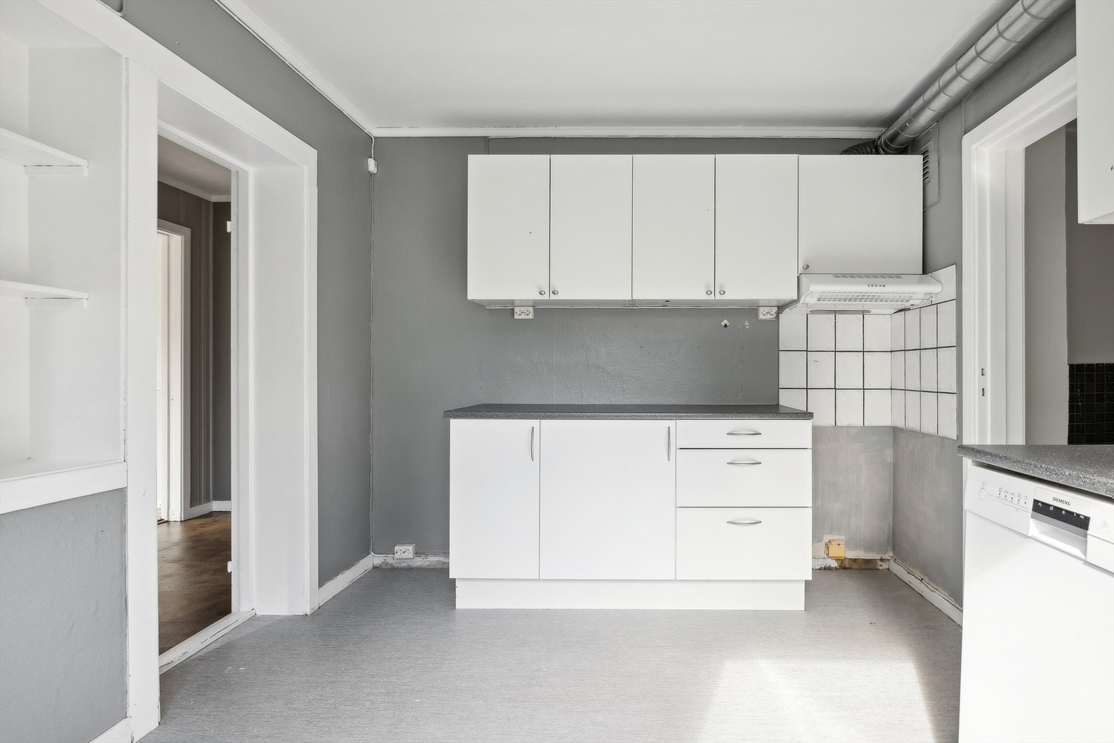 Kjøkkenet i første etasje har innredning med glatte fronter og et overskap med glass i dører og hyller på siden, benkeplate av laminat og det er plass til kjøleskap, oppvaskmaskin og komfyr. Rommet fremstår praktisk med lagringsplass i skuffer og hyller. Galleribilde