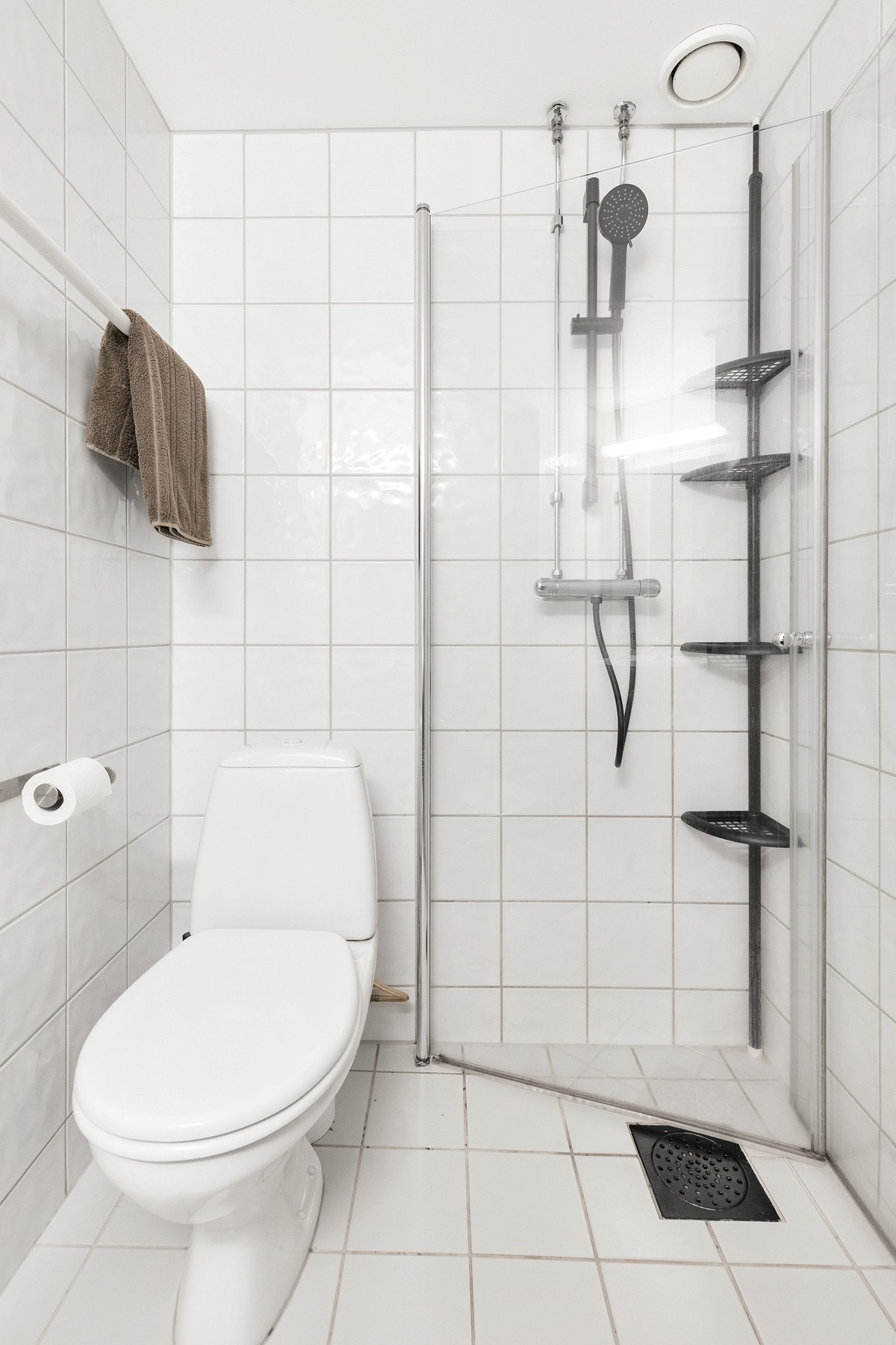 Badet er innredet med gulvstående toalett, servant med underskap og dusjhjørne Galleribilde