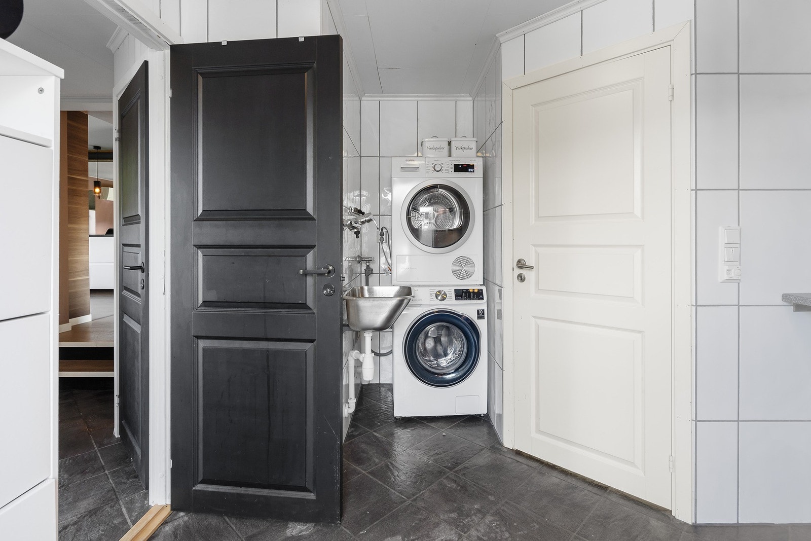 Romslig vaskerom med adkomst både fra entre og egen inngang. Den hvite døren leder til baderom med toalett og dusj. Galleribilde