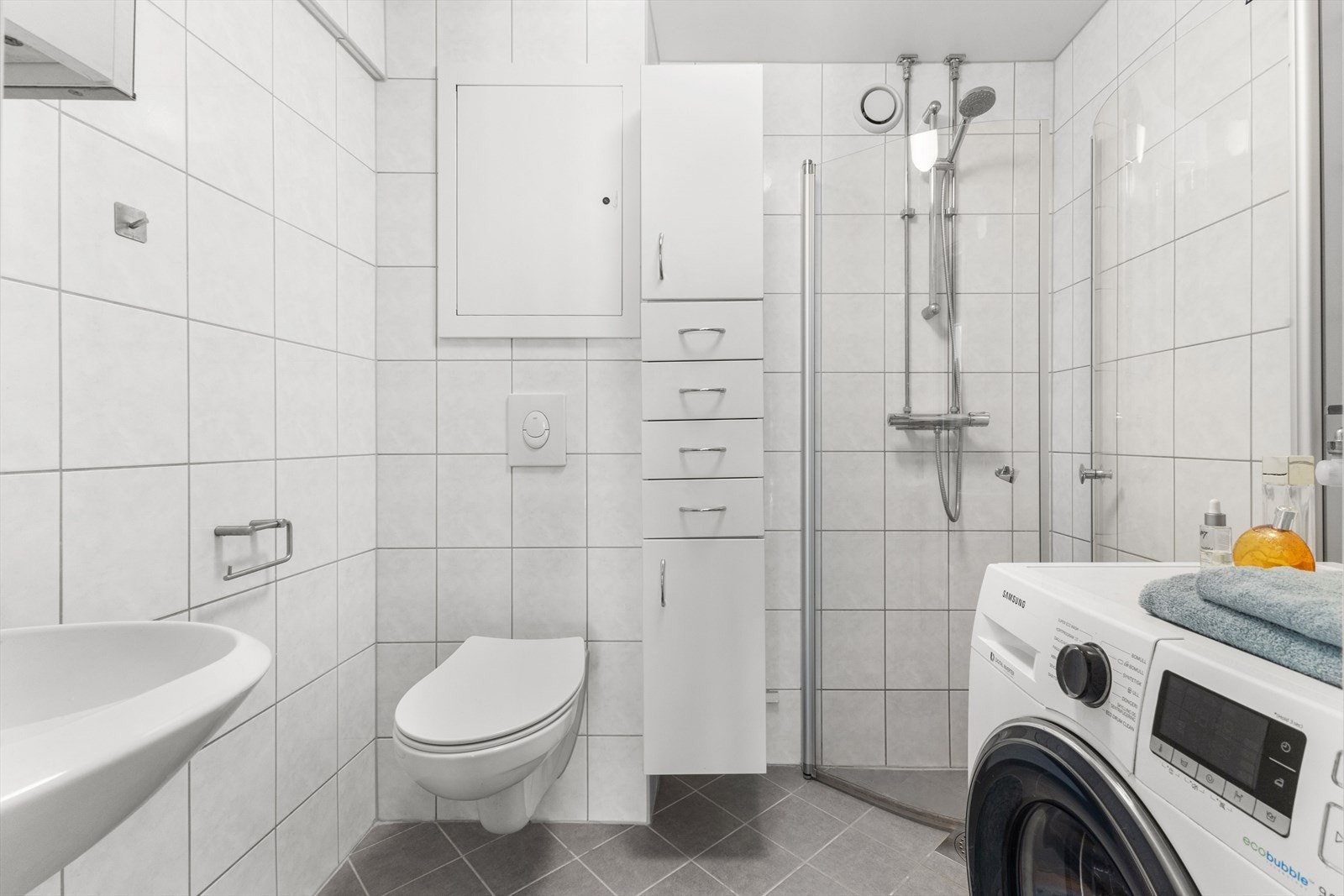 Pent flislagt baderom med vannbåren gulvvarme, rehabilitert i 2014 i regi av borettslaget. Badet er innredet med vegghengt klosett, servant og dusjhjørne med svingbare dører. Galleribilde
