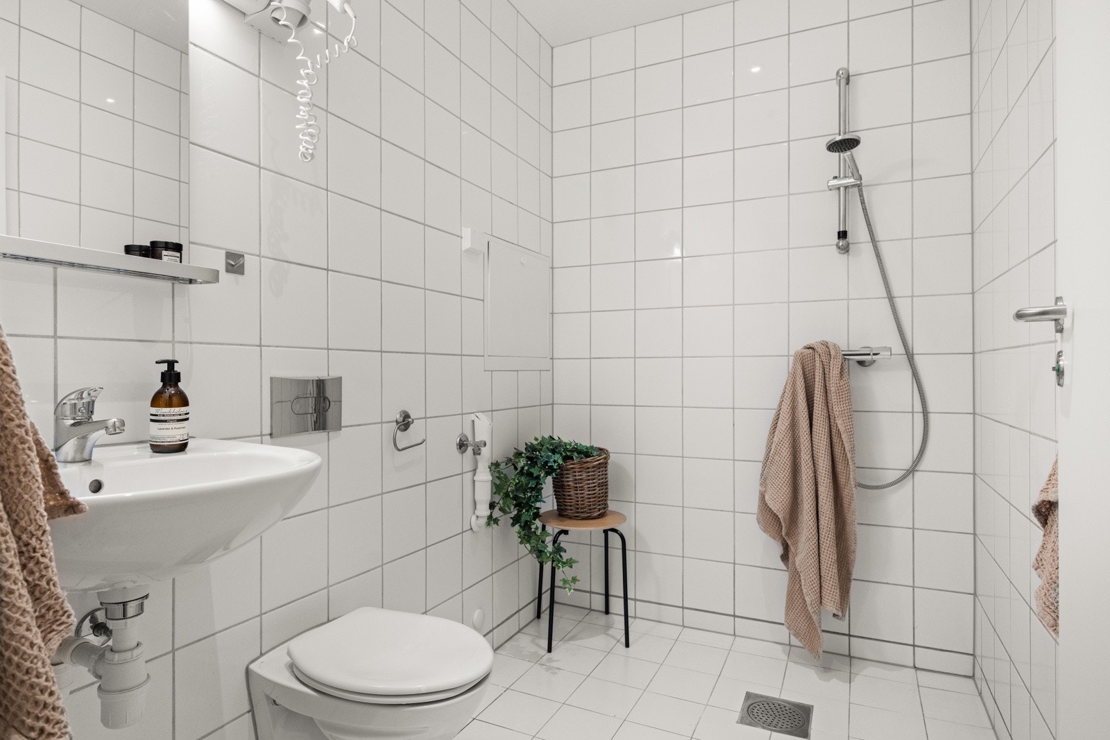 Baderommet er utstyrt med vegghengt servant med speil og belysning over, vegghengt dusj, vegghengt toalett og opplegg for vaskemaskin. Galleribilde