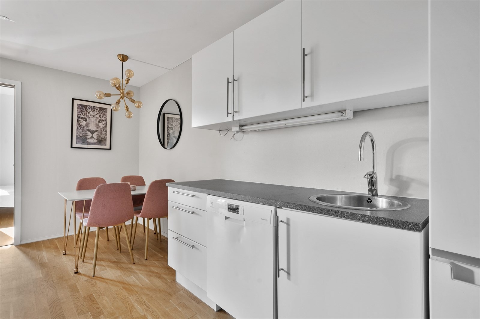 Innredning i hvit utførelse med glatte fronter og medfølgende hvitevarer (komfyr, oppvaskmasking og kjøl-/fryseskap). Kjøkkenet har også god, tilliggende spiseplass. Galleribilde