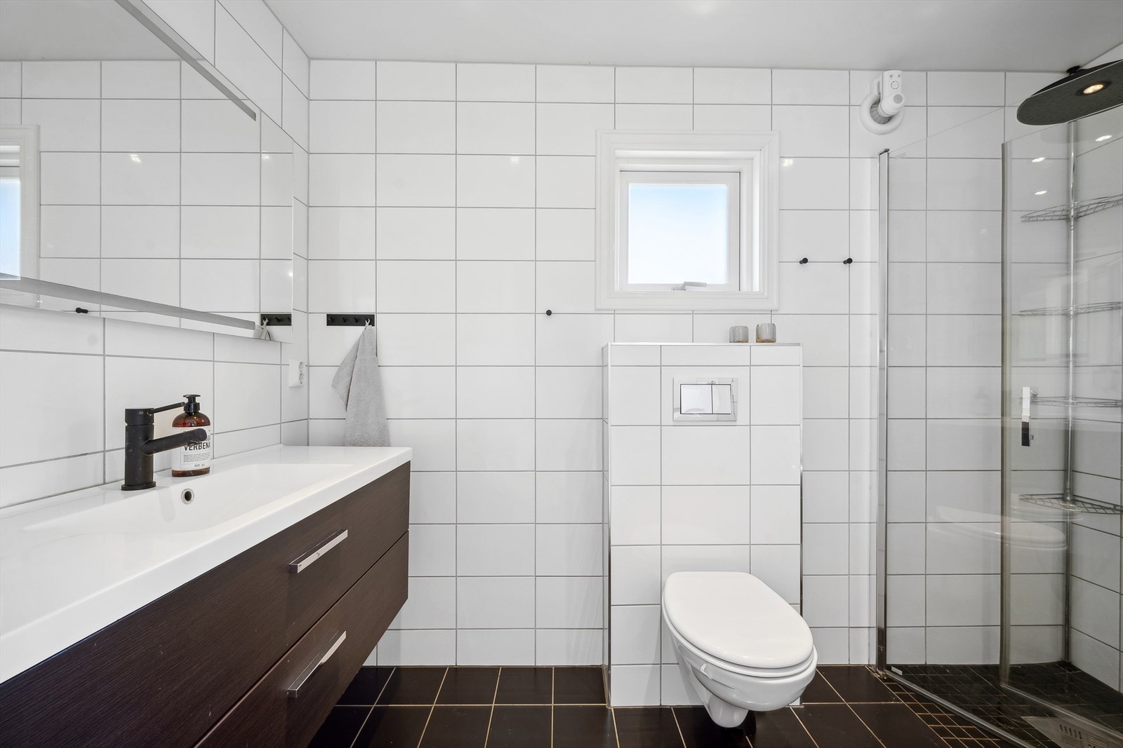 Leiligheten har et elegant og flott baderom med flislagt gulv med elektriske varmekabler. Veggene har fliser. Taket er malt. Badet har veggmontert toalett og dusjhjørne med innfellbare glassdører. Galleribilde