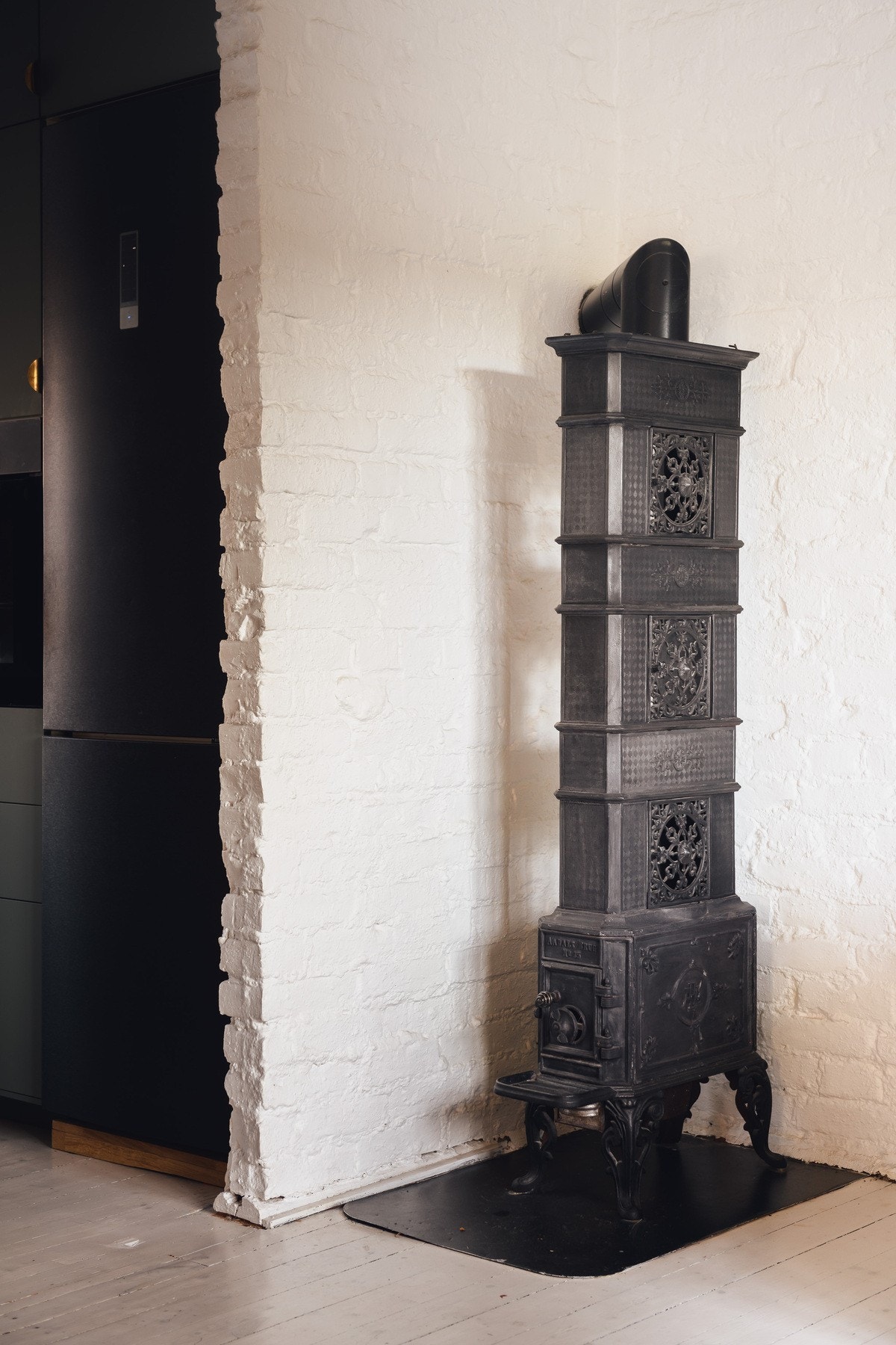 I hjørnet av stuen står en vakker etasjeovn, et element som både gir varme og dekor. Med den nyinstallerte varmepumpen, blir imidlertid denne brukt mest for kos Galleribilde