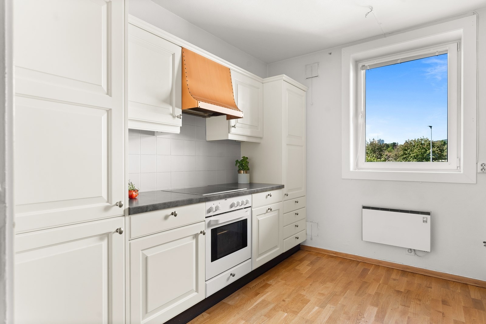 Kjøkkenet har profilerte lyse fronter og integrerte hvitevarer som koketopp, stekeovn, oppvaskmaskin og kjøl/frysekap. Galleribilde