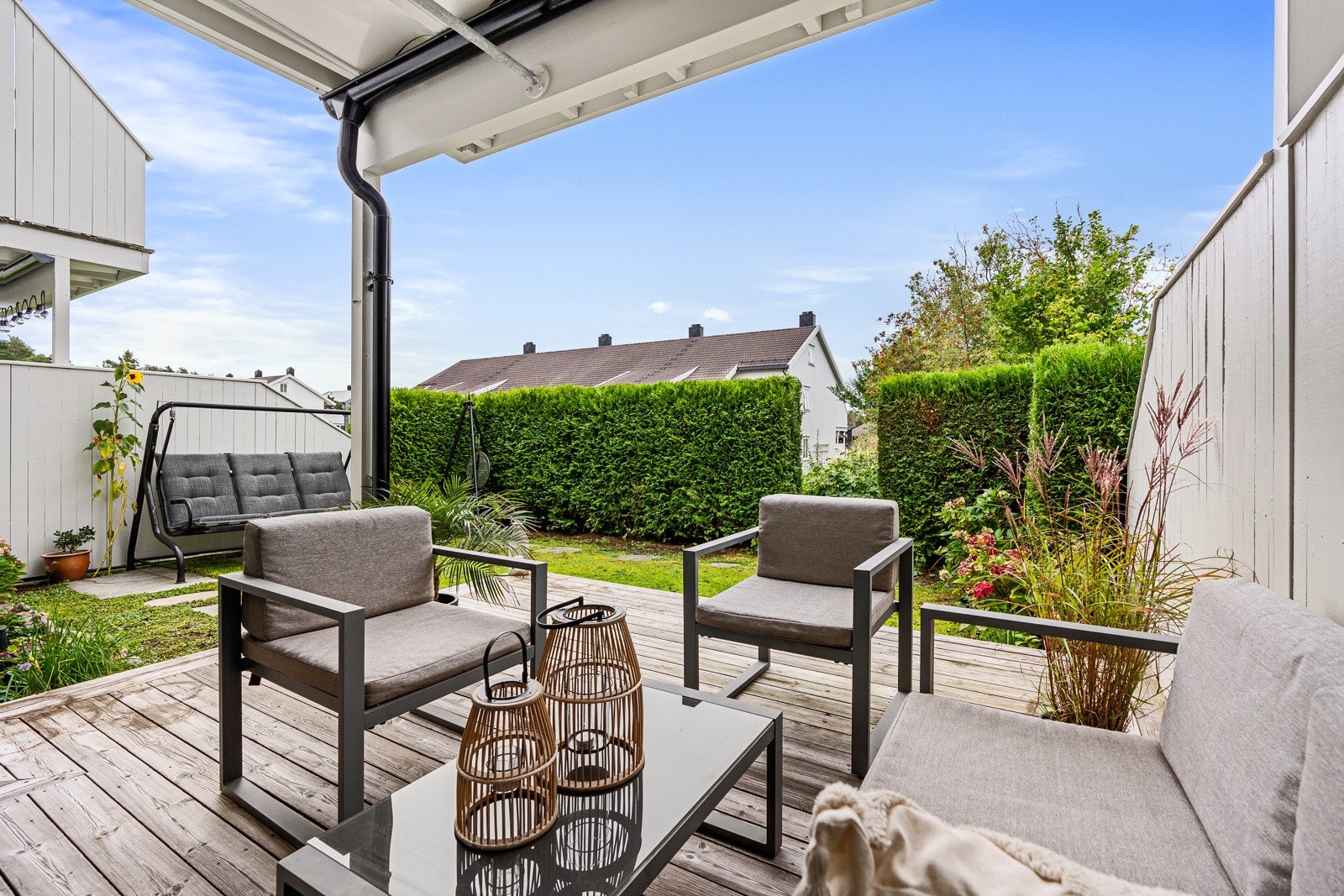 Solrik uteplass med både terrasseplatting og gressplen med hekk Galleribilde