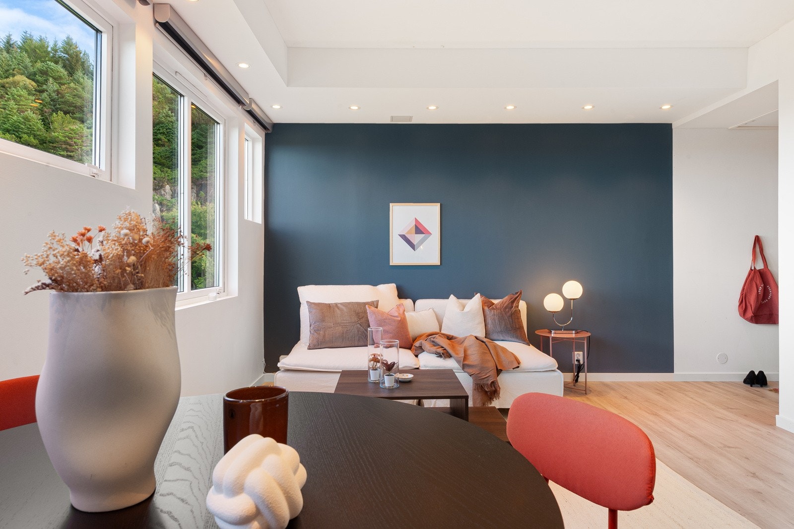 Tiltalende stue med moderne fondvegg, som skaper en fin kontrast til de lysmalte overflatene. Det er plass til sittegruppe og spisestuebord. Legg merke til den flotte lyskassen med downlights. Galleribilde