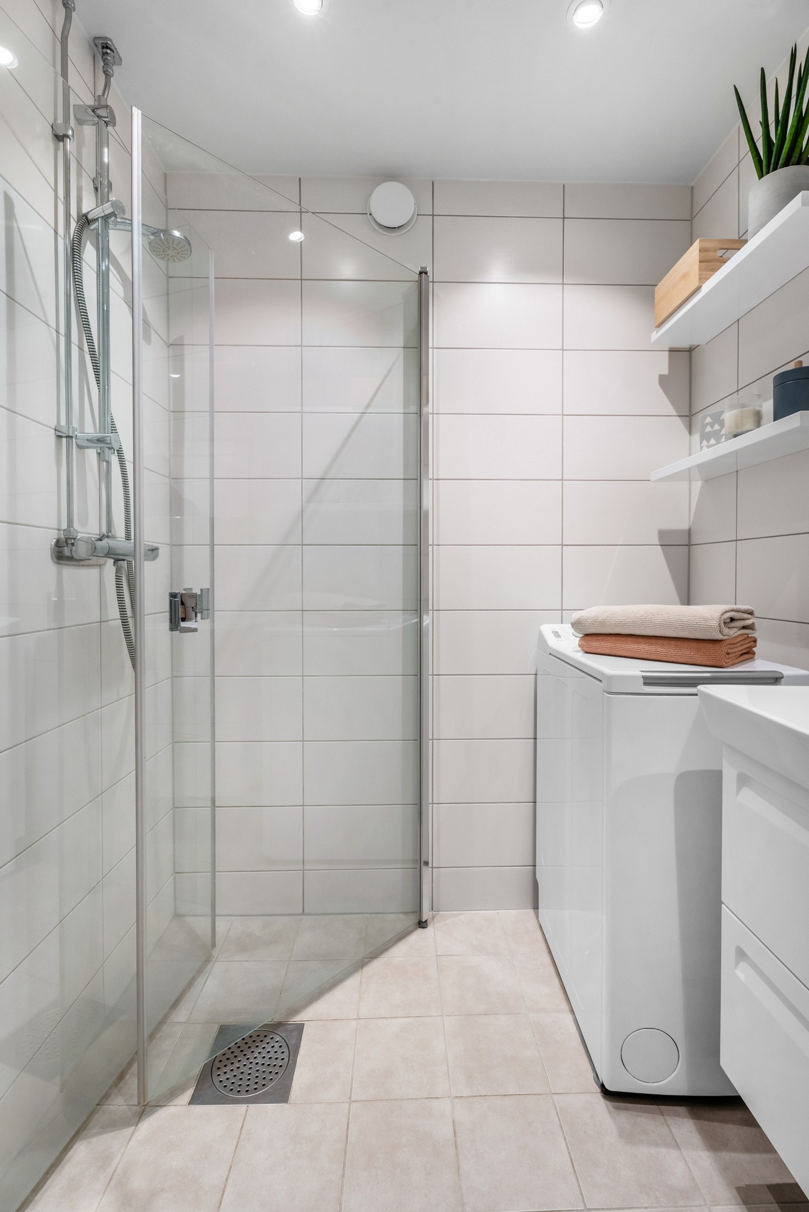 Videre er badet utstyrt med vegghengt toalett, servant med innredning og dusjhjørne med innfellbare glassdører. Galleribilde