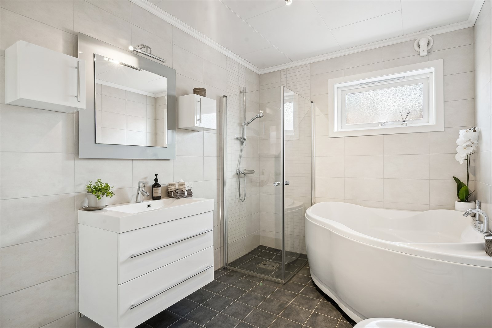 Hovedbadet ligger i 1. etasje og har god plass. Det er innredet med badekar, dusj, vegghengt klosett og servantinnredning Galleribilde