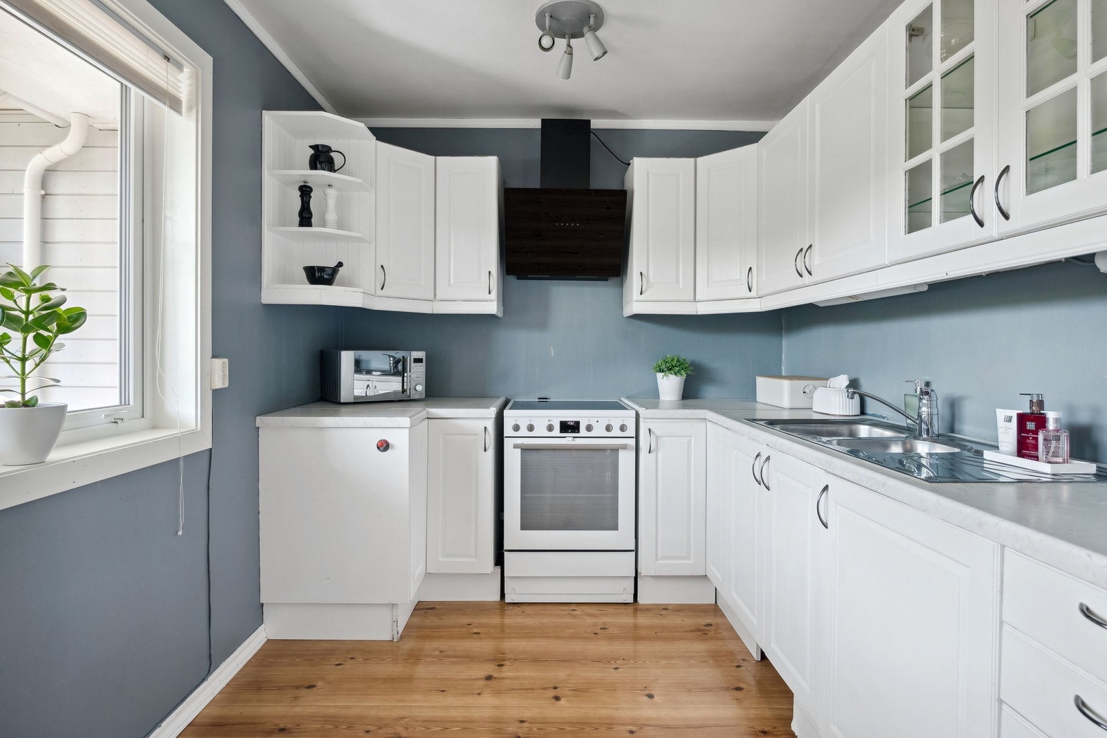 Lyst og innbydende kjøkken som innehar en fast innredning med malte ,profilerte fronter og laminat benkeplate Galleribilde